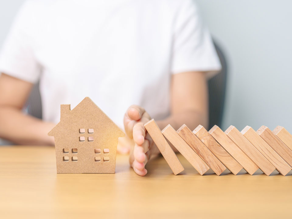 Eine Hand stoppt umfallende Bausteine.