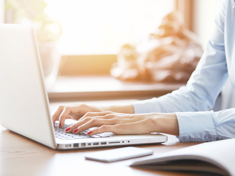 Hände schreiben auf einem Laptop.