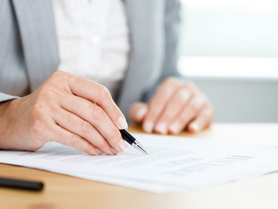 eine Hand hält einen Stift und unterschreibt ein Dokument